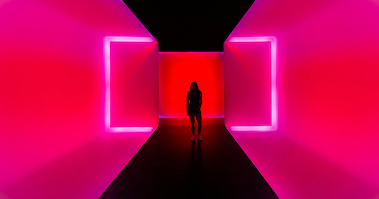 A shadow of a lady standing in a passageway made of neon lights