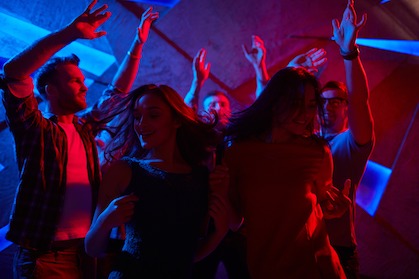 A group of people in a club dancing with their hands up
