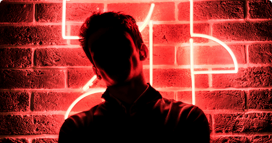 A shadow of a man standing behind neon lights
